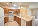 Modern kitchen with oak cabinets, white appliances, and tile floors. Open to living room at 5950 Barbosa Dr # 8, North Las Vegas, NV 89031