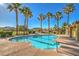 Community pool with mature palm trees and nearby structures on a sunny day at 5950 Barbosa Dr # 8, North Las Vegas, NV 89031