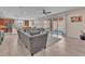 Open-concept living room with a large sofa, tile floors, and sliding glass doors to the backyard at 6659 Alder Flower Ct, North Las Vegas, NV 89084