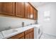 Well-lit laundry room with wooden cabinets, white countertop, sink, and modern washer and dryer at 6728 Regency Ridge Ct, Las Vegas, NV 89148