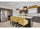 This kitchen is equipped with modern appliances, brown cabinets, barstool seating, and elegant countertop finishes at 7208 Grace Estate Ave, Las Vegas, NV 89113