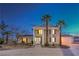 Grand two-story home with stately pillars, palm trees, and an inviting entrance at dusk at 7477 Ullom Dr, Las Vegas, NV 89139