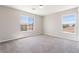 Empty bedroom has neutral carpet and walls, with two large windows and natural light at 7857 Midnight Ride St, Las Vegas, NV 89131