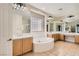 Well-appointed bathroom with dual sinks, a soaking tub, a glass block window, and plenty of mirrors at 8305 Chapelle Ct, Las Vegas, NV 89131