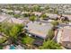 Wide aerial view showcases a backyard with covered patio, lush grass, mature trees, desert landscaping, and a pool at 8504 Mystic Night Ave, Las Vegas, NV 89143