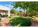 Beautiful backyard with healthy green lawn, mature trees, and covered patio with outdoor seating at 8504 Mystic Night Ave, Las Vegas, NV 89143