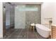 Modern bathroom featuring a glass-enclosed shower, soaking tub, and sleek, marbled accent wall at 8504 Mystic Night Ave, Las Vegas, NV 89143