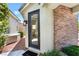 Front entrance to house featuring black framed glass door, brick accents, and green landscaping at 8504 Mystic Night Ave, Las Vegas, NV 89143