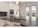 Close up of a bright kitchen with a large island and a stainless steel farmhouse sink with gold faucet at 8504 Mystic Night Ave, Las Vegas, NV 89143