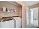Functional laundry room with washer, dryer, shelving and bifold doors at 9328 Jumpin Juniper Ave, Las Vegas, NV 89129