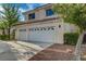 Three-car garage of a tan two-story home with a concrete driveway at 9772 Galahad Point Ct, Las Vegas, NV 89147