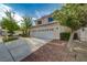 Tan two-story home featuring a three-car garage and desert landscaping at 9772 Galahad Point Ct, Las Vegas, NV 89147