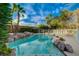 Inviting pool with rock accents and mature palm trees, offering a tranquil retreat in a lush backyard at 9772 Galahad Point Ct, Las Vegas, NV 89147