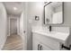 Stylish bathroom with white vanity, updated fixtures, and wood-look flooring leading to hallway at 113 Elm St, Henderson, NV 89015