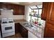 Well-lit kitchen featuring tile countertops, dual sink, gas range, wood cabinetry, and window at 2898 Violet Ln # 0, Henderson, NV 89074