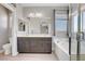 Bathroom with double vanity, large mirror, soaking tub, and glass shower door at 626 Taliput Palm Pl, Henderson, NV 89011