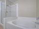 Bathroom featuring a soaking tub with shower, complemented by white tile at 713 Wheat Ridge Ln # 102, Las Vegas, NV 89145