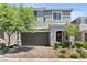 Charming two-story home featuring a gray facade, manicured landscaping, and a brick driveway at 7456 Tinley Creek Ave, Las Vegas, NV 89113