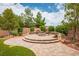 Inviting backyard with brick patio, stone fire pit, seating, and lush landscaping offers space for relaxation at 8340 Jeremiahs Lodge Ave, Las Vegas, NV 89131