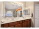 Bathroom vanity featuring double sinks, wood cabinets, and a large mirror with vanity lights at 8340 Jeremiahs Lodge Ave, Las Vegas, NV 89131