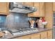 Gas cooktop on granite countertop with custom backsplash and stainless hood at 9900 Summer Ash Ct # 101, Las Vegas, NV 89134