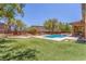 Beautiful backyard features pool, water feature, stone patio, and artificial grass at 9992 Peak Lookout St, Las Vegas, NV 89178