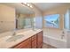 Bright bathroom featuring a double sink vanity, soaking tub, and large window at 10072 Pelham Park Ave, Las Vegas, NV 89148