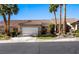 Charming single-story home featuring a two-car garage, landscaped front yard, and desert landscaping with vibrant palm trees at 1187 Mohave Dr, Mesquite, NV 89027