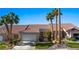 Charming single-story home with a two-car garage, well-manicured lawn, and desert landscaping with vibrant palm trees at 1187 Mohave Dr, Mesquite, NV 89027
