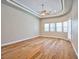 Spacious bedroom with hardwood floors, ceiling fan, tray ceiling, and natural light from many windows at 213 Villa Borghese St, Las Vegas, NV 89138