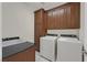 Functional laundry room featuring dark wood cabinets, granite counters, washer, and dryer at 2753 Kildrummie St, Henderson, NV 89044