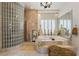 Elegant soaking tub with tile surround, glass block shower, and plantation shutters for natural light at 277 Dark Forest Ave, Las Vegas, NV 89123