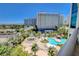 Balcony view featuring palm trees, a pool, and hotel buildings, offering an urban oasis at 322 Karen Ave # 601, Las Vegas, NV 89109