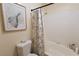 Bright bathroom featuring tiled shower with floral curtain, plus a toilet and decorative framed art at 3236 Manzanita Ln, Laughlin, NV 89029