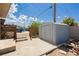 View of the backyard showing a shed, brick pavers, a fire pit, chairs, and desert landscaping at 67 Oklahoma Dr, Henderson, NV 89015