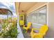 Cozy front porch with yellow chairs, a vibrant yellow door, and charming desert foliage at 67 Oklahoma Dr, Henderson, NV 89015