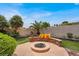 A cozy firepit with outdoor seating surrounded by lush landscaping and palm trees at 7511 Bridlehorne Ave, Las Vegas, NV 89131