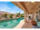 A covered patio seating area overlooks the luxurious pool and backyard at 7511 Bridlehorne Ave, Las Vegas, NV 89131