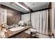 Stylish bathroom with brown tile, a large mirror, and a sink with a spacious countertop at 7625 Raven Hills Dr, Las Vegas, NV 89149