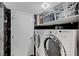Efficient laundry room with modern appliances, shelving, and stylish black and white patterned tile at 7625 Raven Hills Dr, Las Vegas, NV 89149