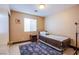 Neutral bedroom with a single bed, small side table, blue rug, and a window at 7801 Olympus Ave, Las Vegas, NV 89131