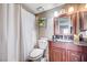 Bathroom featuring dark wood vanity, granite countertop, decorative shelving and white shower curtain at 7952 Diamond Rock Way # 102, Las Vegas, NV 89128