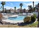 Community pool surrounded by lush landscaping and palm trees under a bright blue sky at 7952 Diamond Rock Way # 102, Las Vegas, NV 89128