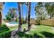 Green backyard with a lush lawn, mature palm trees, and stone fire pit at 8113 Gothic Ave, Las Vegas, NV 89117
