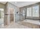 Luxurious primary bathroom featuring a glass shower and a soaking tub near shuttered windows at 8113 Gothic Ave, Las Vegas, NV 89117