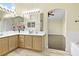 This bathroom features a double sink vanity with oak cabinets, tile floors, and archway to the bedroom with a shower at 8221 Stoneheather Ct, Las Vegas, NV 89117