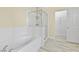 This bathroom offers tile flooring, separate tub and shower with white tile, next to a door to a walk-in closet at 8221 Stoneheather Ct, Las Vegas, NV 89117