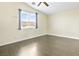 A light-filled bedroom features neutral walls, ceiling fan, hard wood floors, a large window and a high ceiling at 8221 Stoneheather Ct, Las Vegas, NV 89117