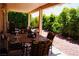 Relaxing covered patio with an outdoor dining set and lush landscaping at 9355 W Viking Rd, Las Vegas, NV 89147