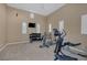 Home gym equipped with various exercise machines and weights, bathed in natural light from the shuttered windows at 10156 Kearney Hill Pl, Las Vegas, NV 89144